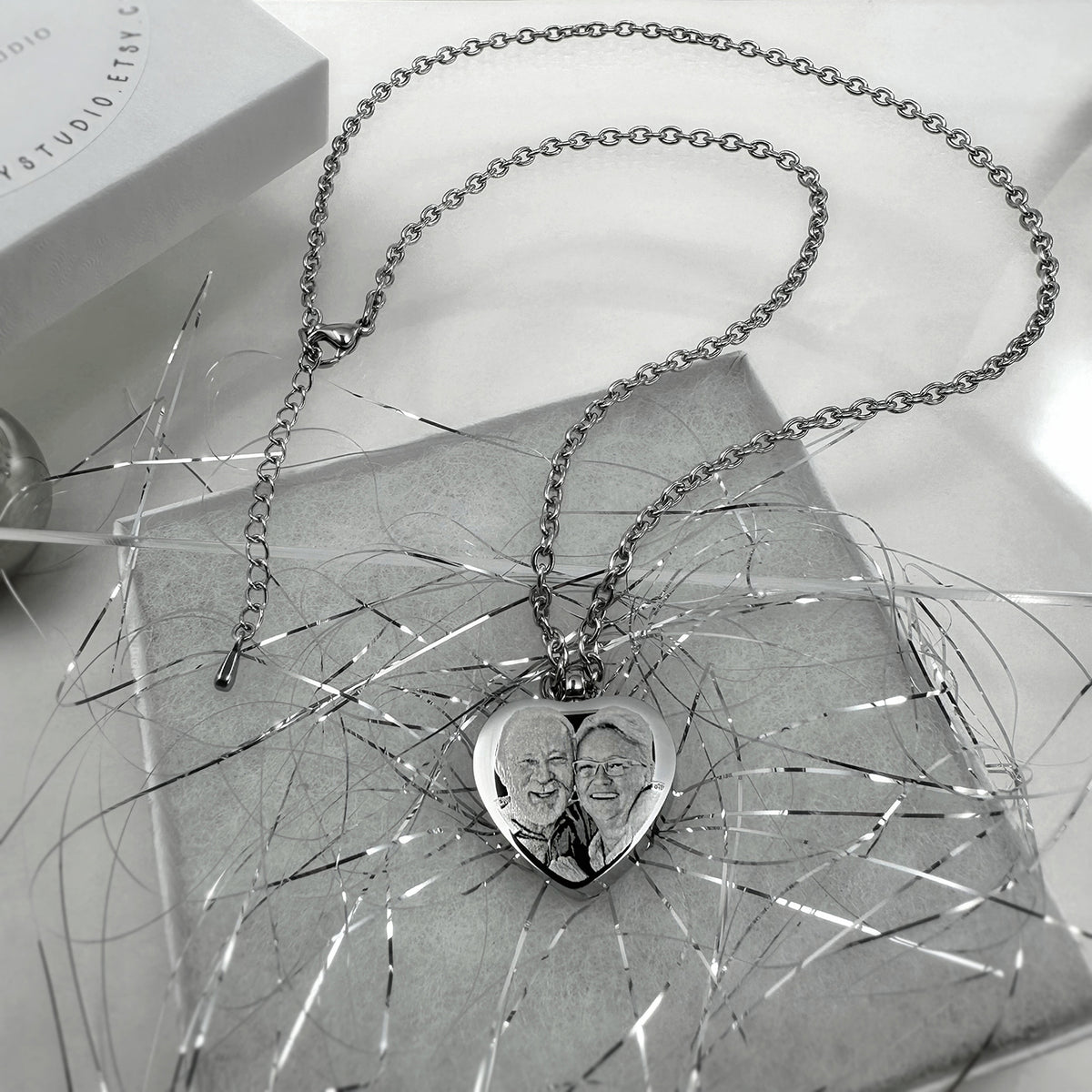 Heart cremation urn necklace with engraved couple portrait styled among silver tinsel and silver chain