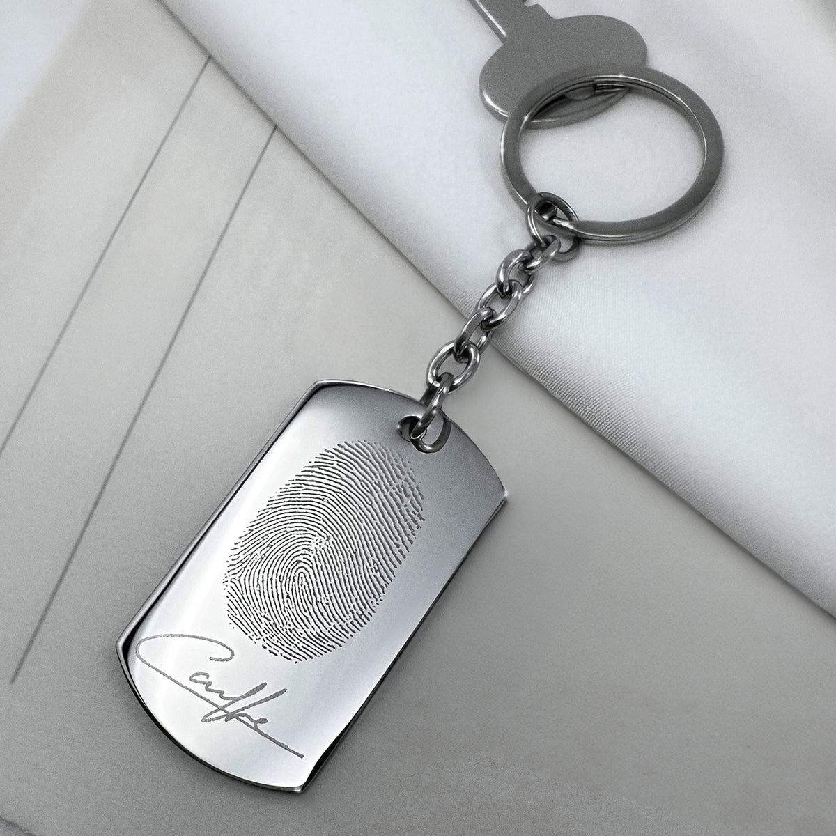 Custom fingerprint dog tag keychain close-up with round keyring, detailed fingerprint, and personalized signature engraving