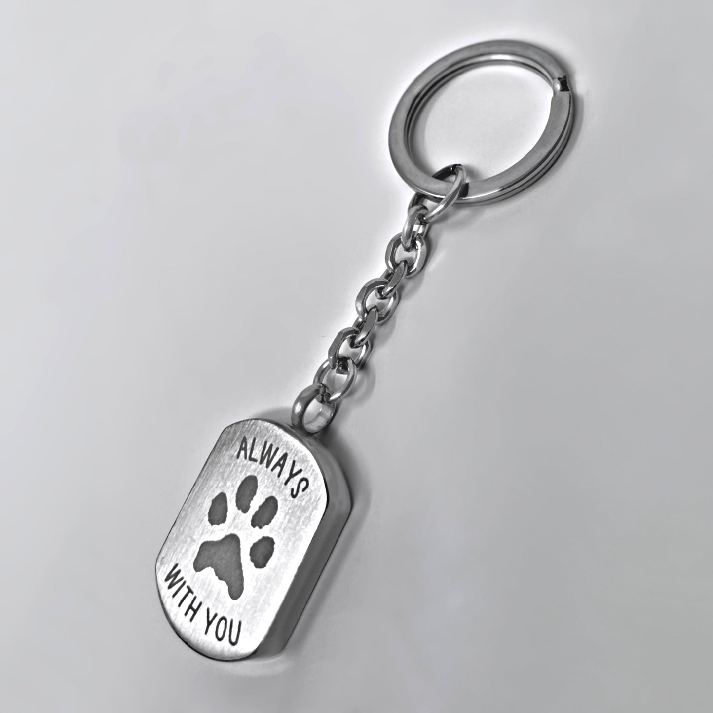 Back of a personalized pet cremation urn keychain engraved with a paw print and memorial message.