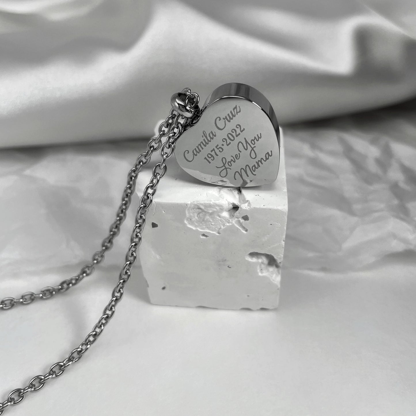 Back of a personalized heart-shaped cremation urn necklace engraved with a custom memorial message.