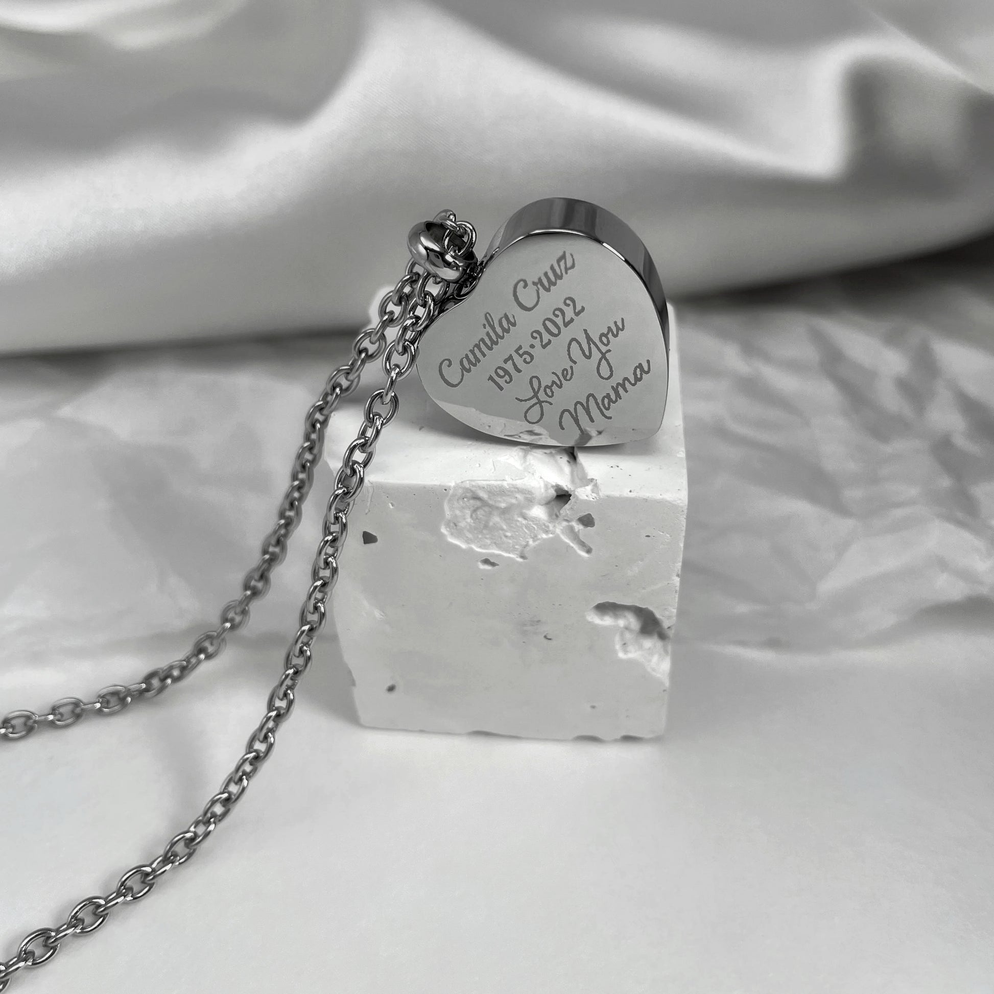 Back of a personalized heart-shaped cremation urn necklace engraved with a custom memorial message.
