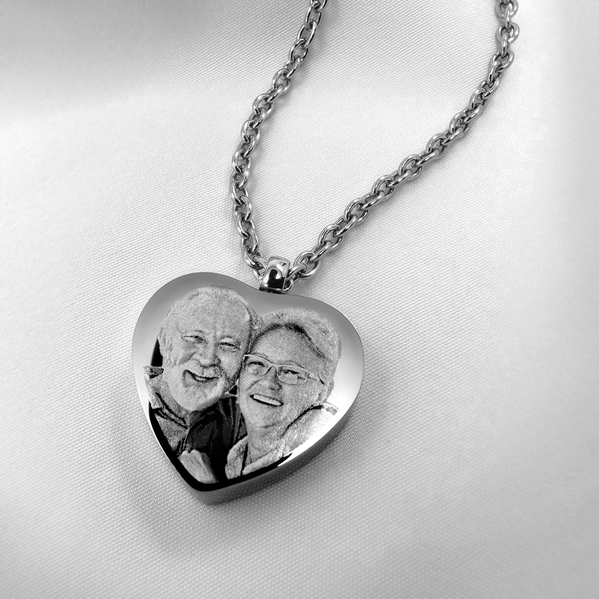 Close-up of a stainless-steel heart urn necklace engraved with a custom family photo.