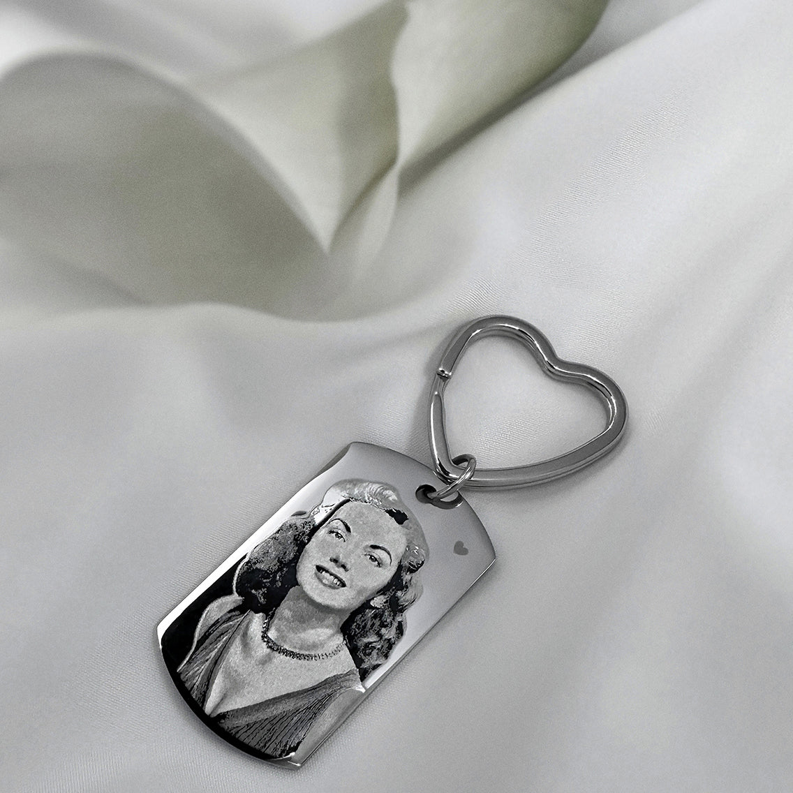 Custom portrait memorial dog tag keychain with heart-shaped keyring displayed on soft fabric