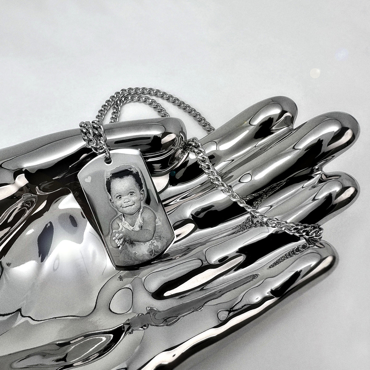 Custom baby portrait picture dog tag necklace displayed on a polished silver tray