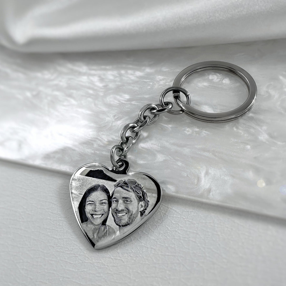 Personalized couple photo heart keychain displayed on a natural shell