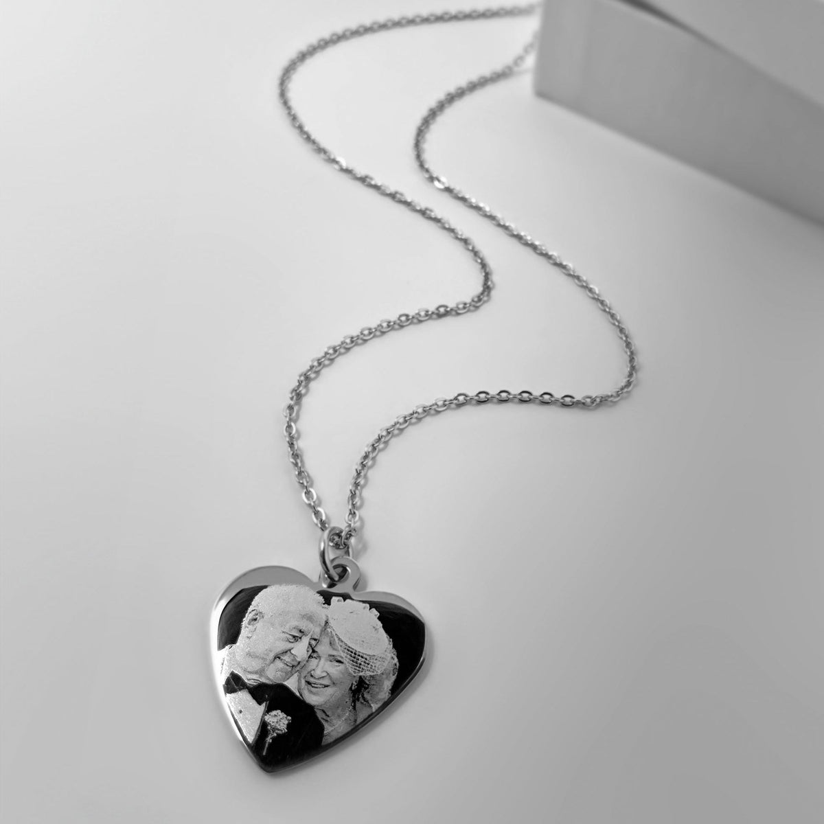 Custom couple photo heart necklace displayed beside a gift box with personalized engraving
