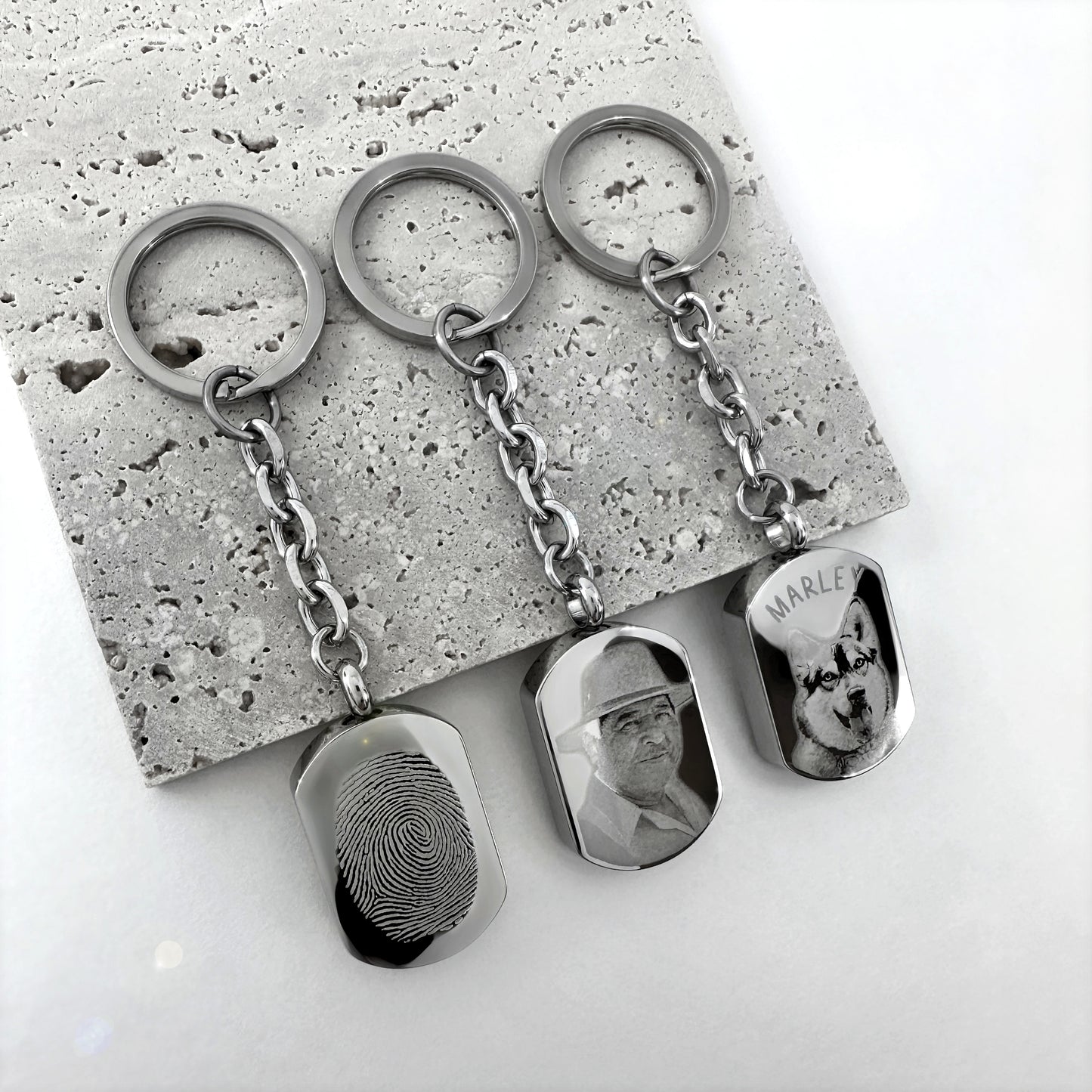 Personalized pet cremation urn keychains engraved with custom dog and cat portraits.