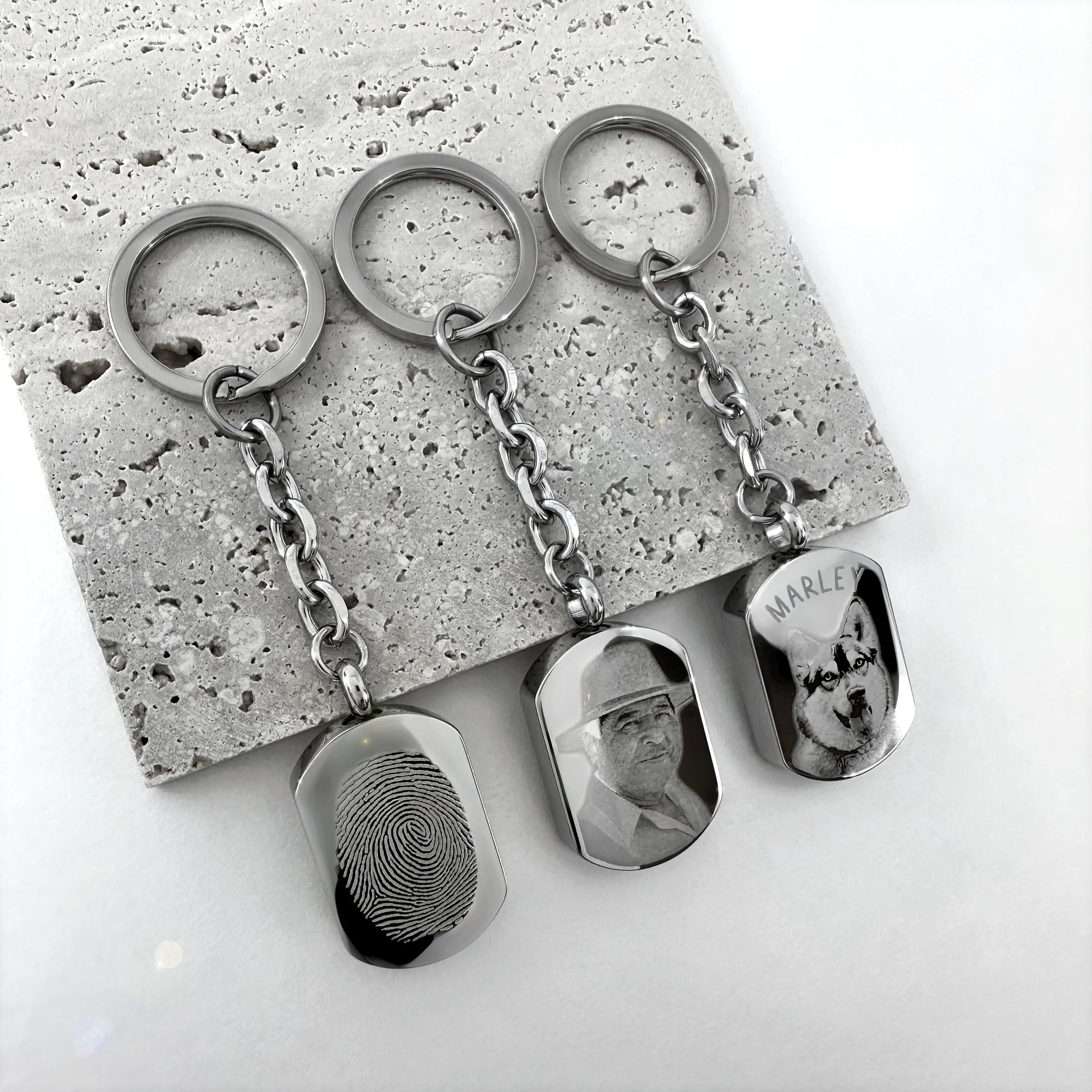 Personalized pet cremation urn keychains engraved with custom dog and cat portraits.