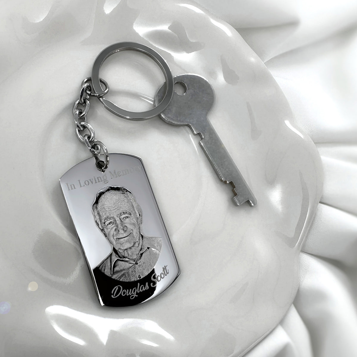 Personalized Dad memorial dog tag keychain with custom portrait engraving displayed beside keys on a white dish