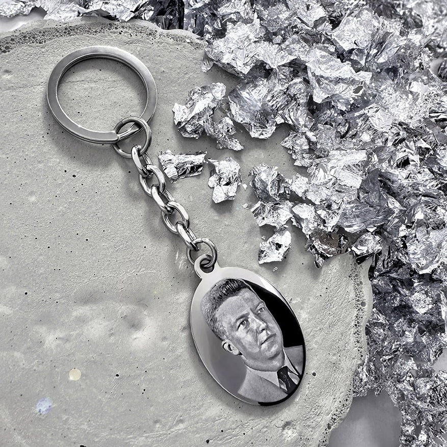 Custom photo oval keychain with engraved portrait displayed in a styled memorial setting