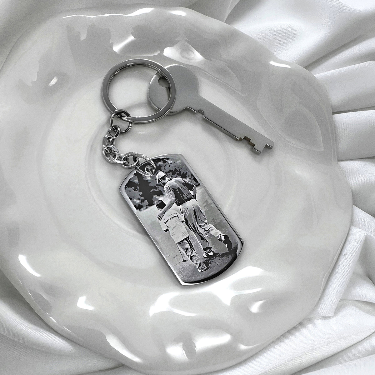 Custom father-and-son photo dog tag keychain displayed with keys on a white dish in a lifestyle setting