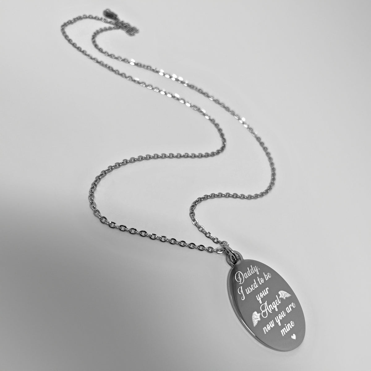 A silver oval pendant necklace with custom memorial engraving 'Daddy I used to be your Angel now you are mine' with small Angel wings and a heart, displayed on a light gray background.