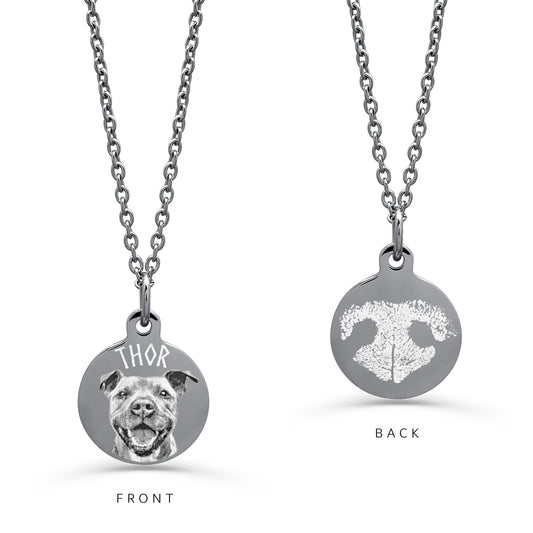 A silver necklace shown from both sides on a white background. The front side features a round pendant with a detailed personalized portrait of a dog and a custom name engraved above it. The other side displays an actual engraved nose print.