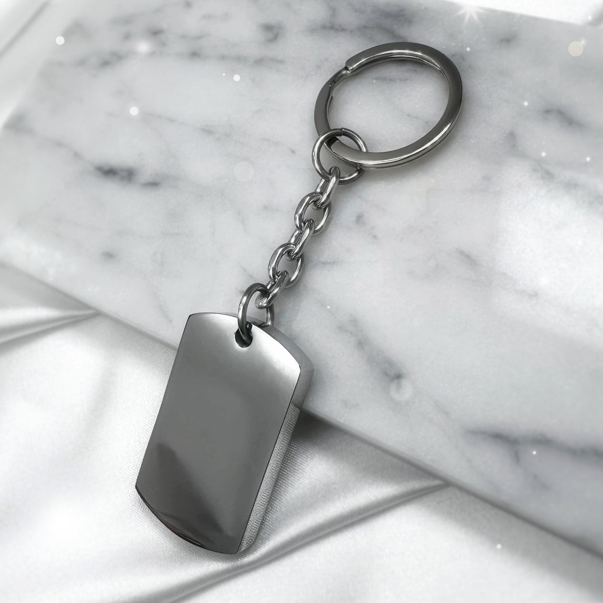 Blank polished stainless-steel dog tag urn keychain displayed on marble