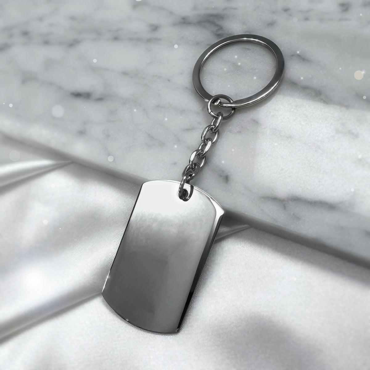 Blank polished dog tag keychain with round keyring displayed on marble and satin