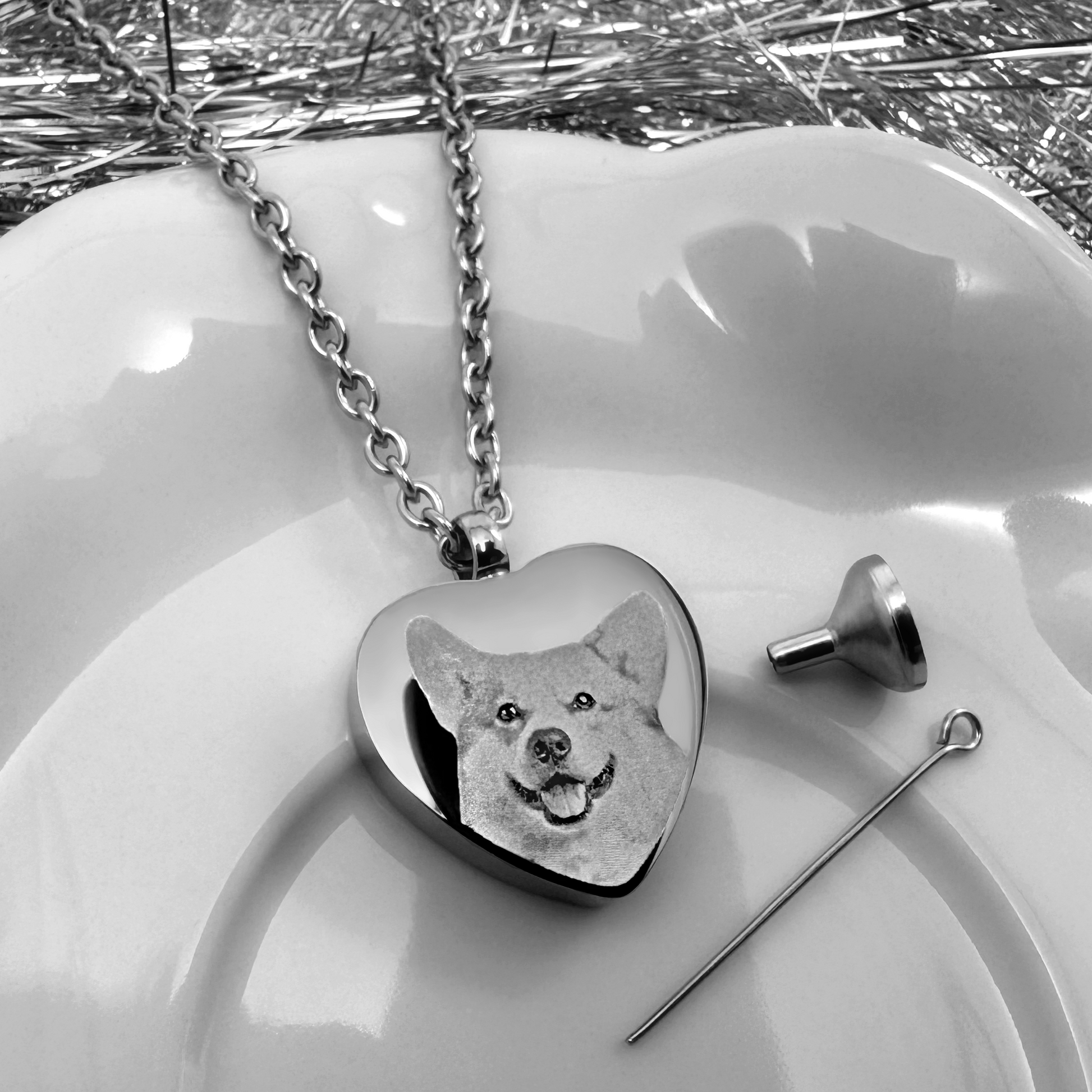 Personalized dog cremation urn necklace displayed with its included fill funnel and pin.