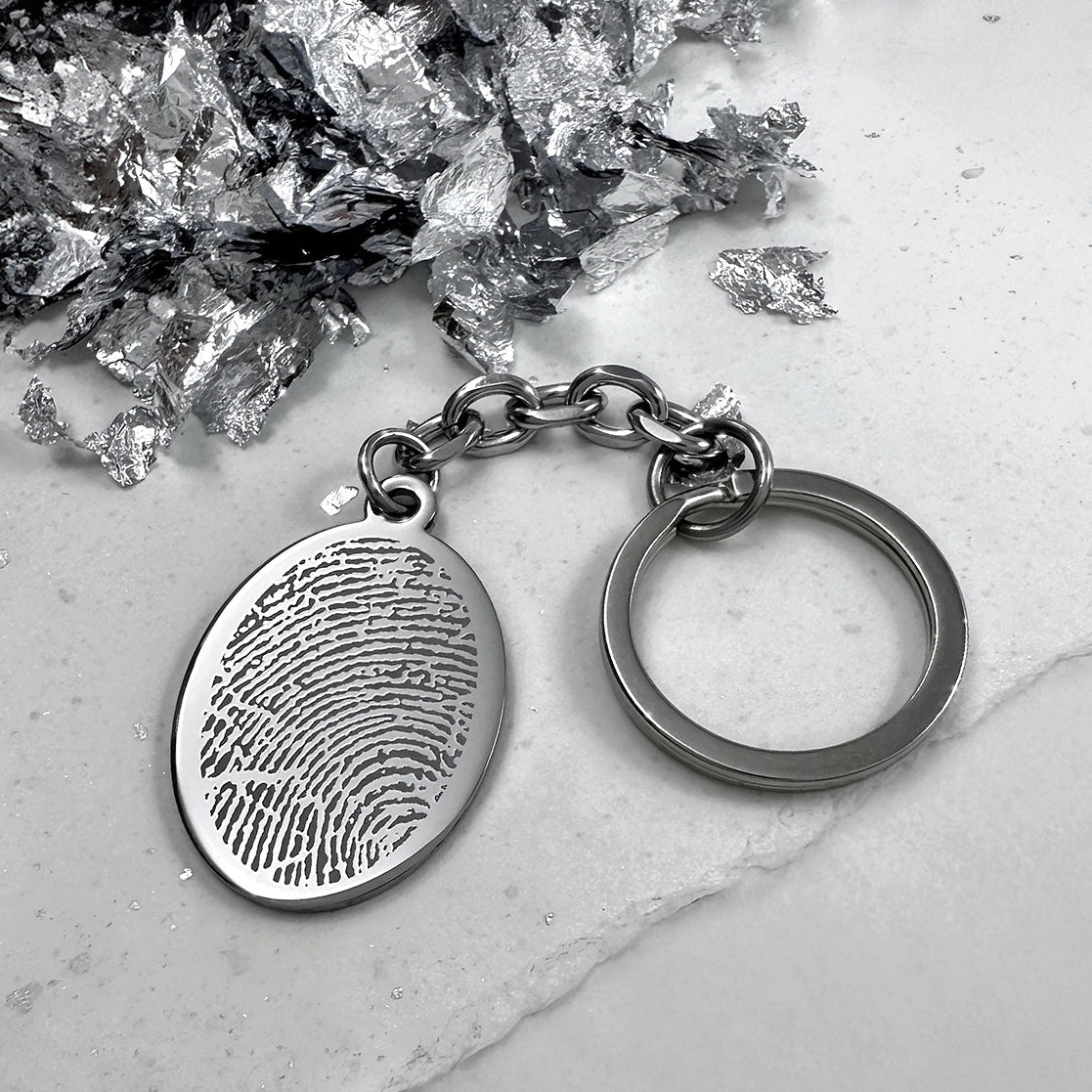 Personalized engraved fingerprint oval keychain shown in a close-up lifestyle display