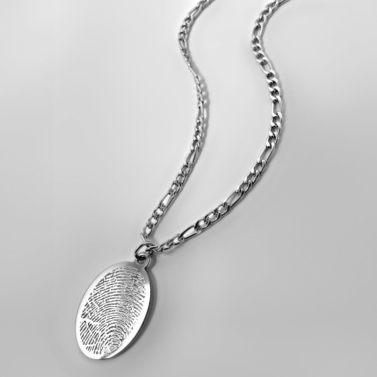 Personalized silver oval necklace with custom fingerprint engraving shown at an angled close-up