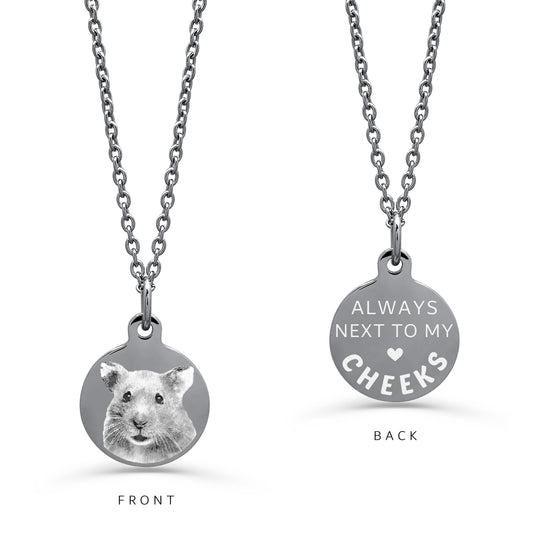 A round silver pendant necklace on a white background. The left 'FRONT' view shows a personalized actual hamster pet portrait, while the right 'BACK' view displays the engraved message 'ALWAYS NEXT TO MY HEART' with a small heart and a pet name.
