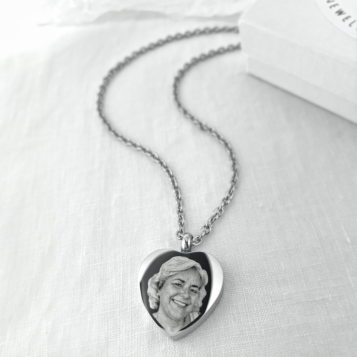 Personalized heart urn necklace with engraved woman’s portrait displayed with silver chain