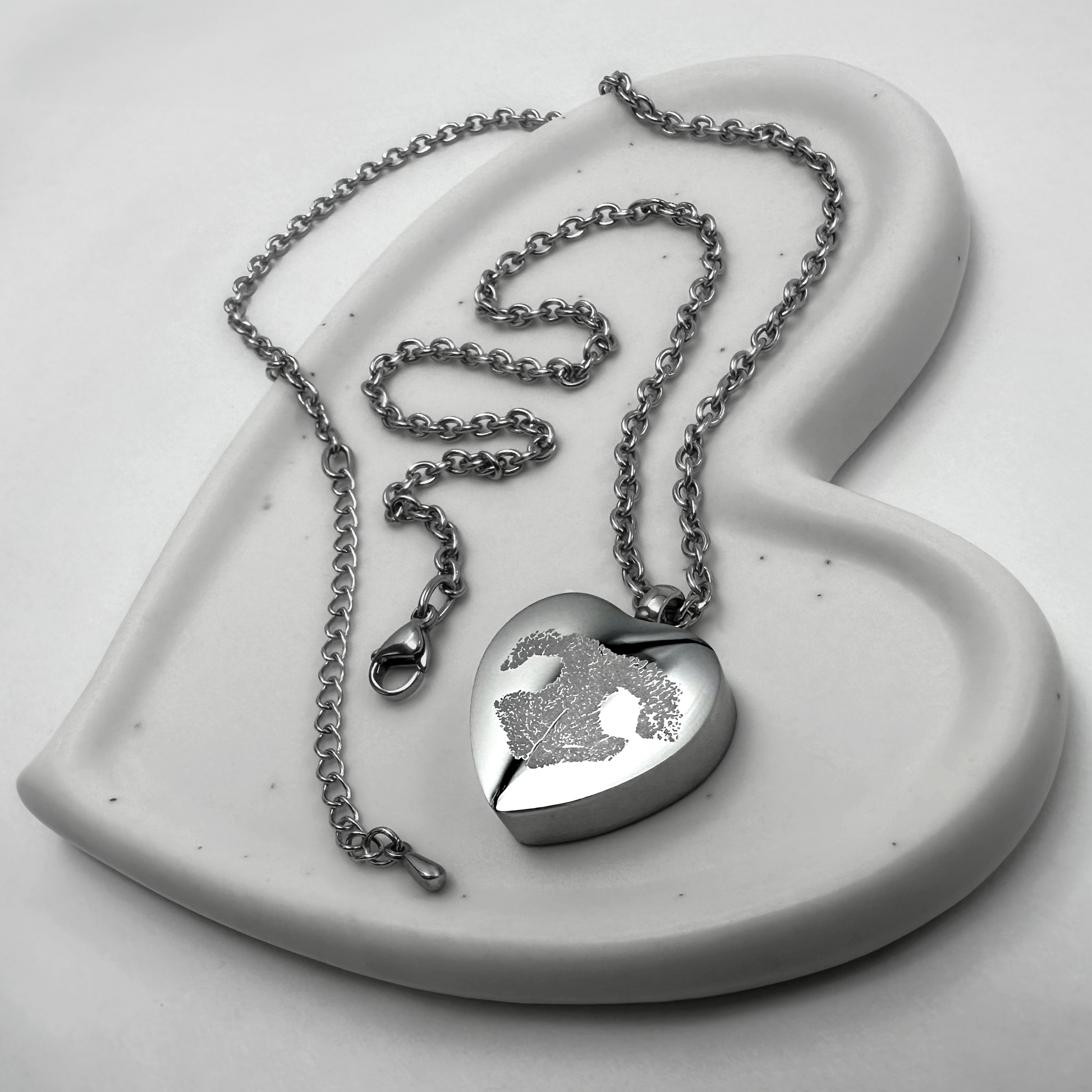 Personalized heart-shaped pet cremation urn necklace engraved with a custom pet nose print on a polished stainless-steel pendant.