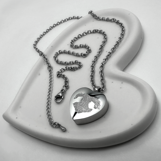 Personalized heart-shaped pet cremation urn necklace engraved with a custom pet nose print on a polished stainless-steel pendant.