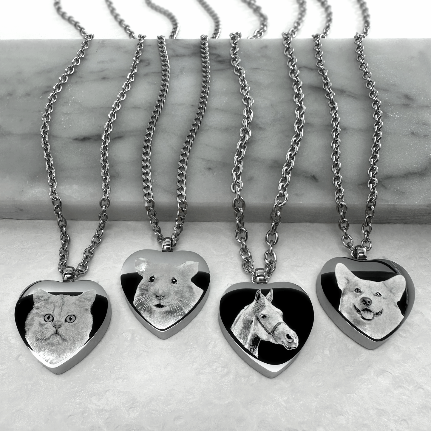 Personalized heart-shaped pet cremation urn necklaces engraved with custom cat, guinea pig, horse, and dog portraits on stainless steel pendants.