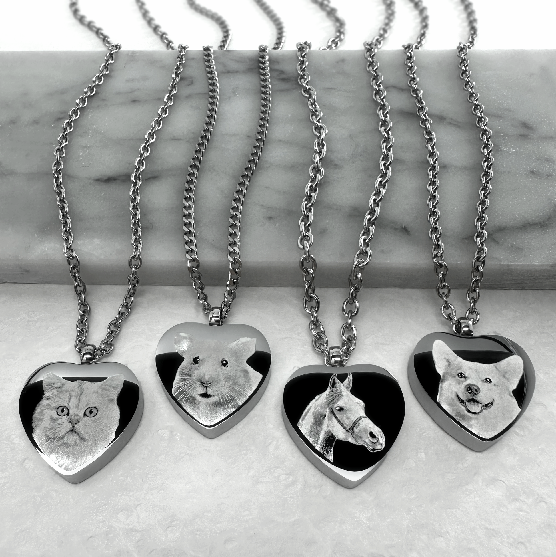 Personalized heart-shaped pet cremation urn necklaces engraved with custom cat, guinea pig, horse, and dog portraits on stainless steel pendants.