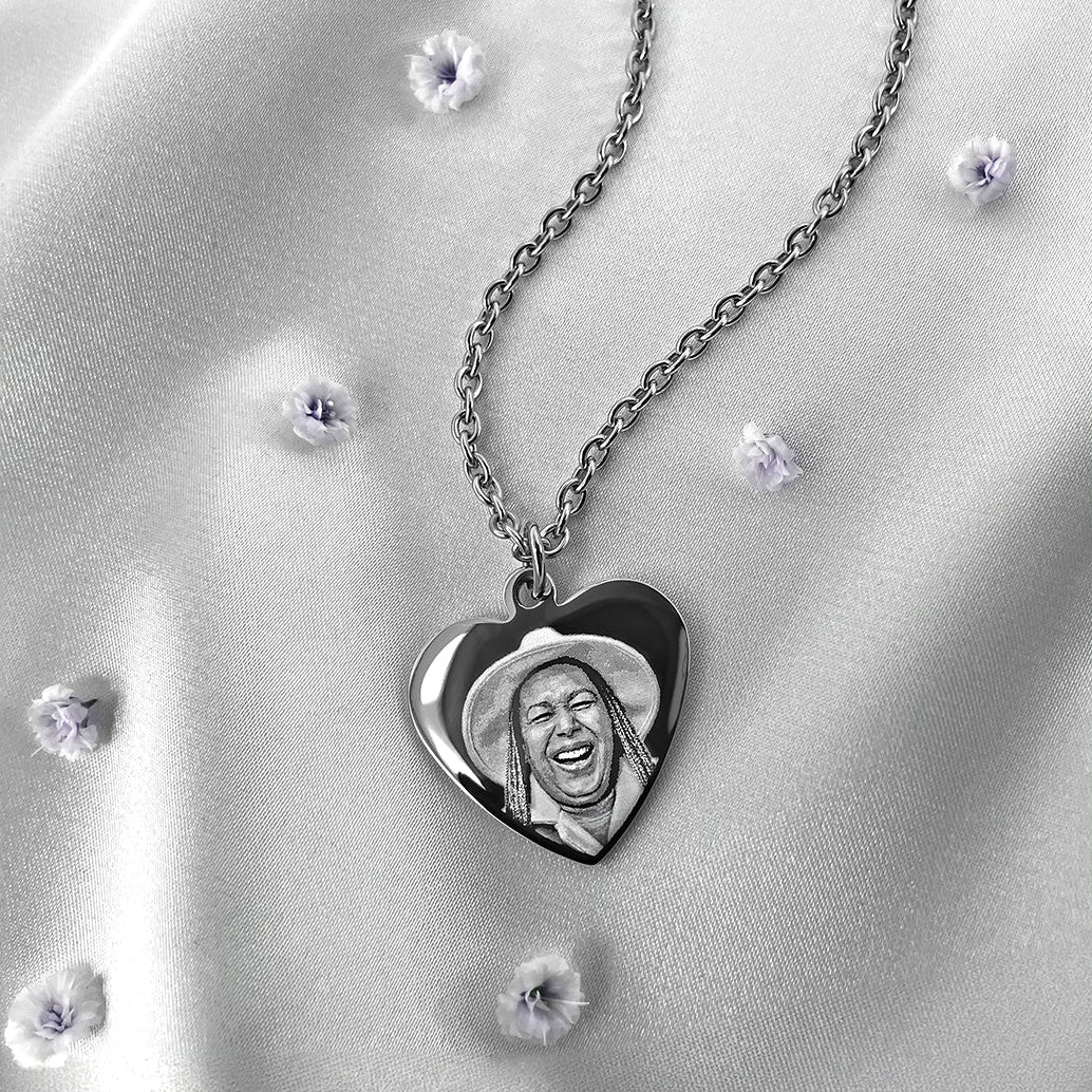 Personalized heart pendant necklace with custom portrait engraving displayed on soft satin