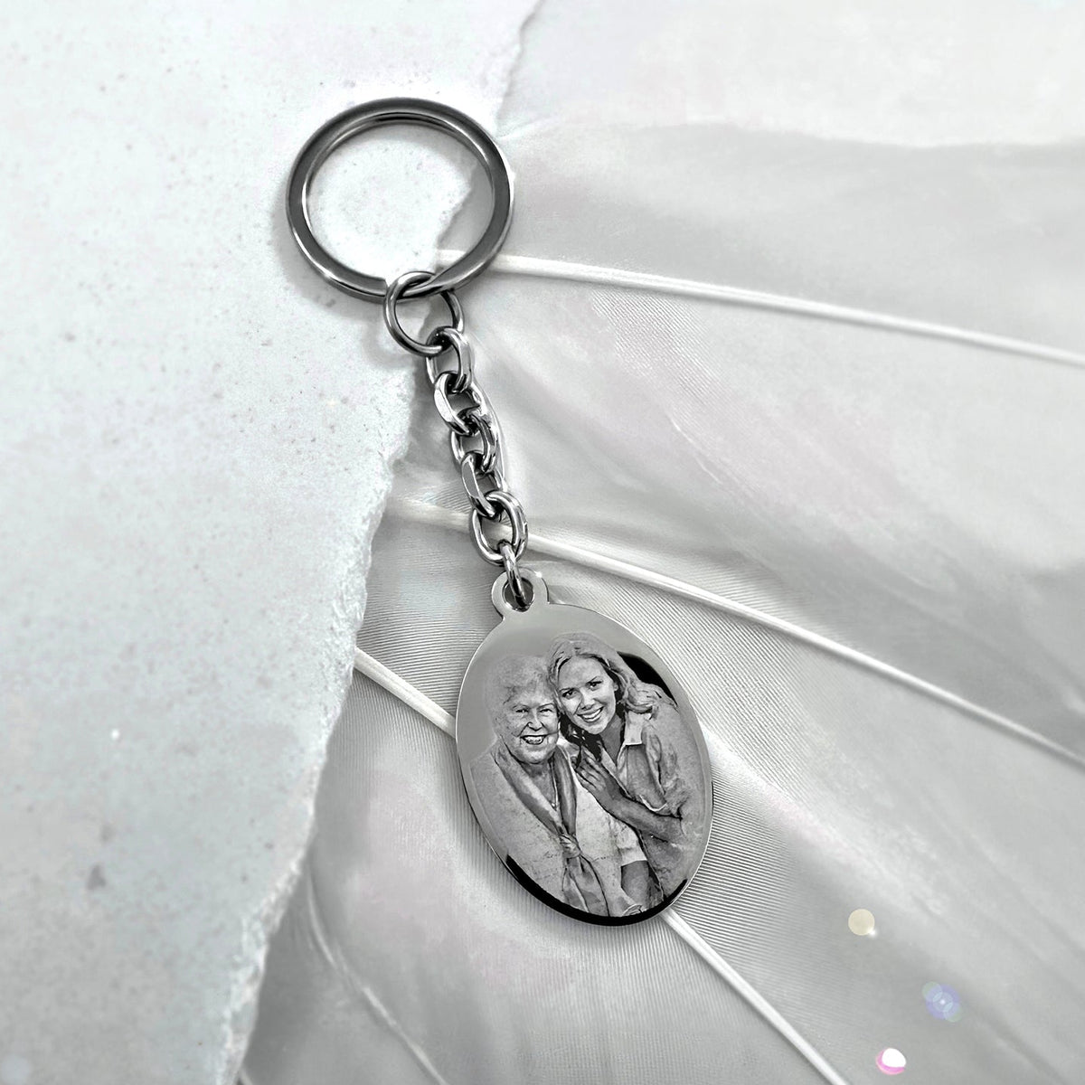 Grandmother and granddaughter engraved memorial oval photo portrait keychain displayed in a soft lifestyle setting
