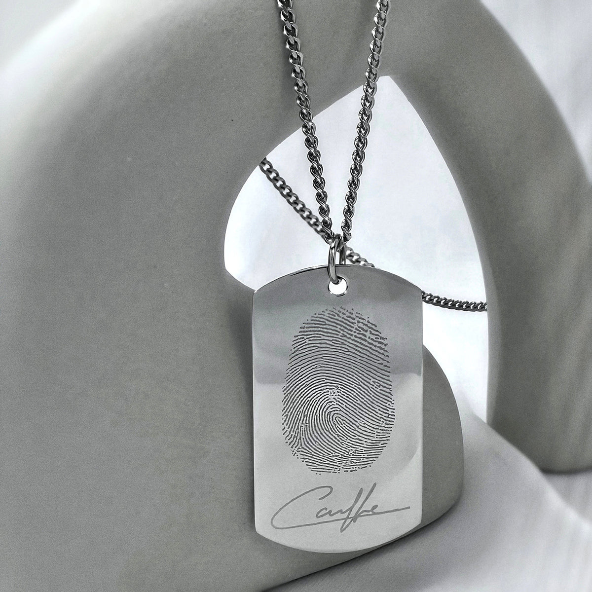 Personalized fingerprint and handwriting dog tag necklace displayed in a modern lifestyle setting