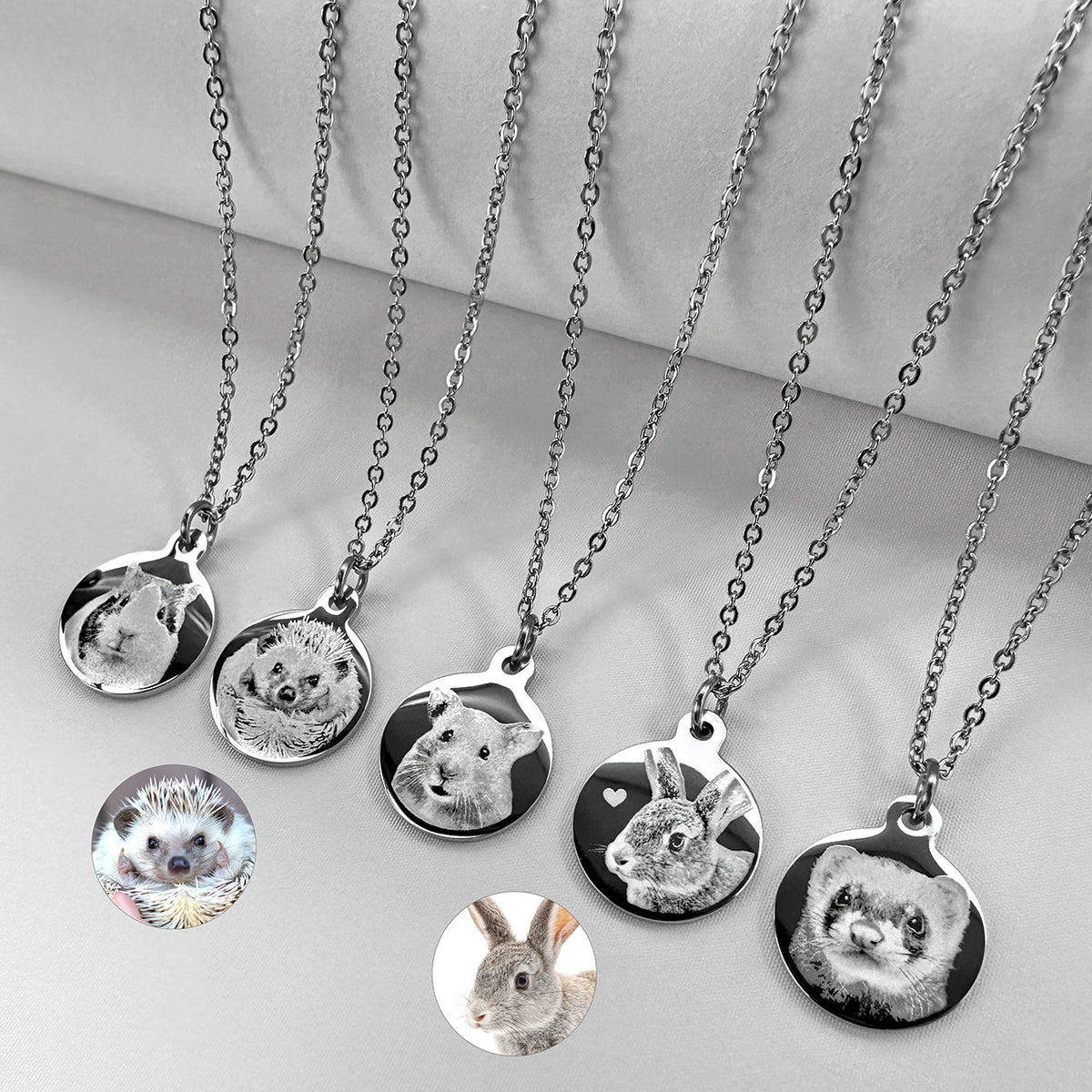 Six silver chain necklaces with round custom pet portrait pendants are arranged on a light gray surface. The pendants display pet photos, including a ferret, rabbit, bunny, hamster, hedgehog, and guinea pig.