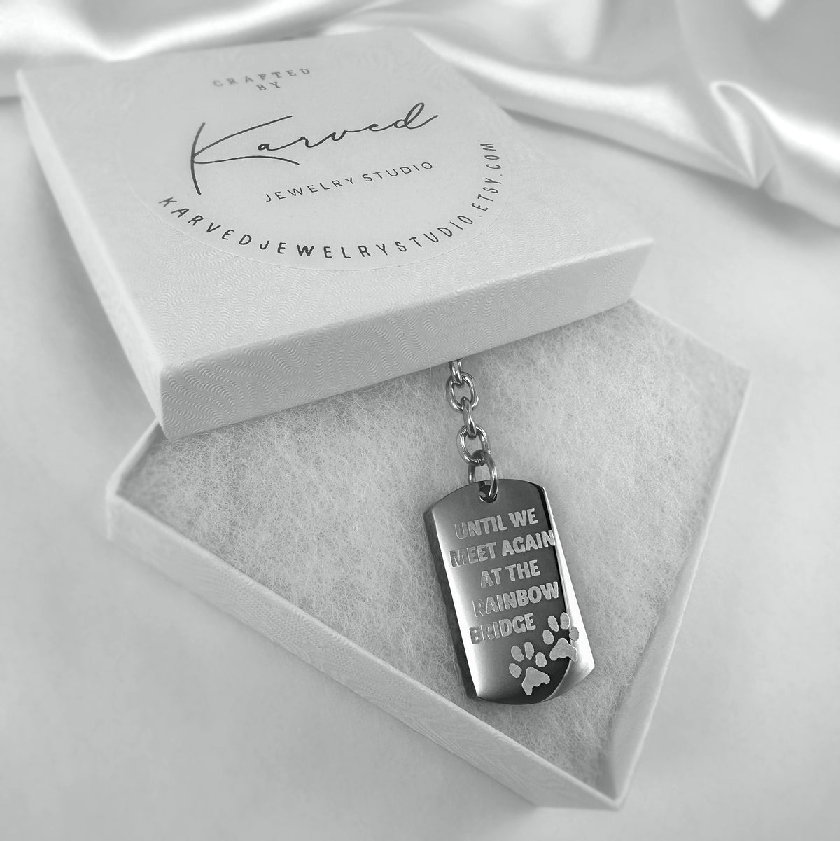 Dog tag urn keychain engraved with memorial design "Until we meet again at the Rainbow Bridge" displayed in a gift-ready box