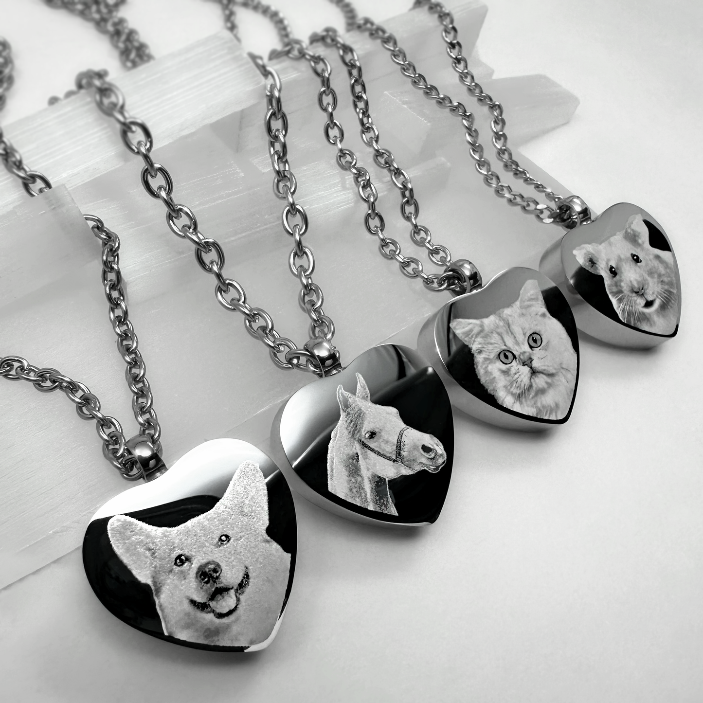 Personalized heart-shaped pet cremation urn necklaces engraved with custom dog, horse, cat, and guinea pig portraits on stainless steel pendants.