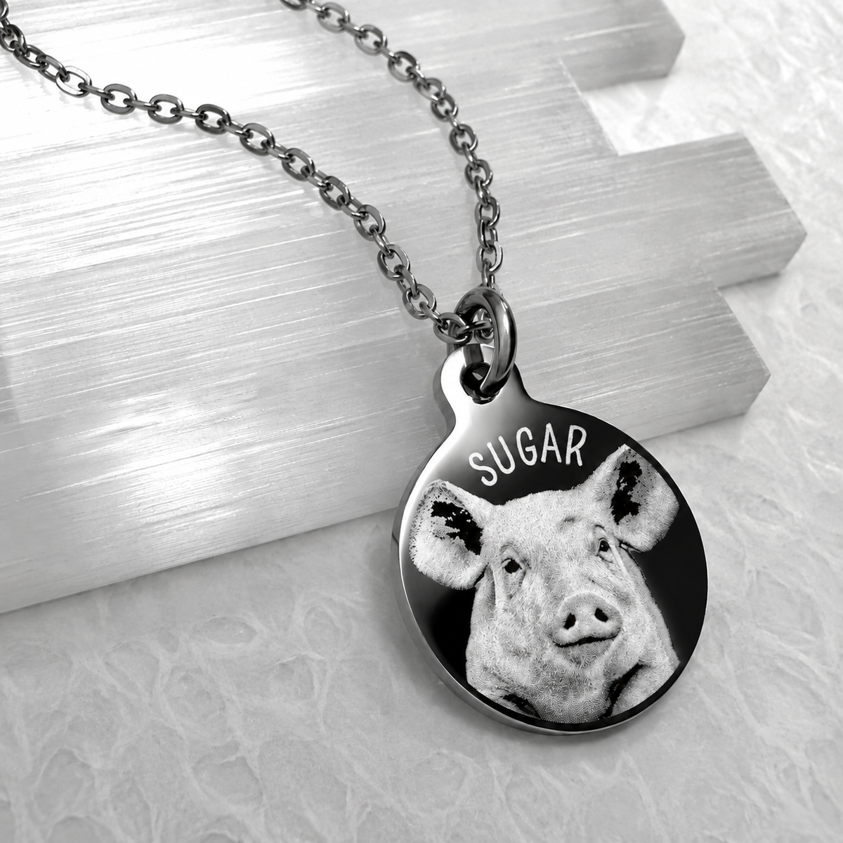 Personalized round pet portrait necklace featuring a pig photo engraved with the custom name Sugar on a polished stainless steel pendant.