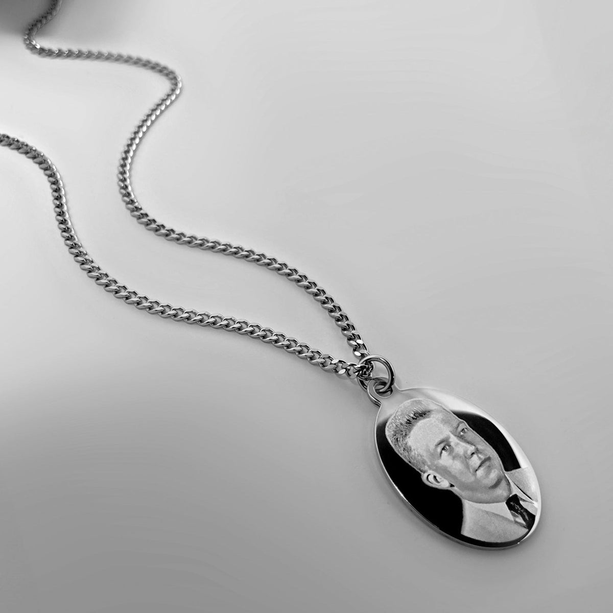 Personalized silver photo oval necklace with custom portrait engraving shown in a styled lifestyle display