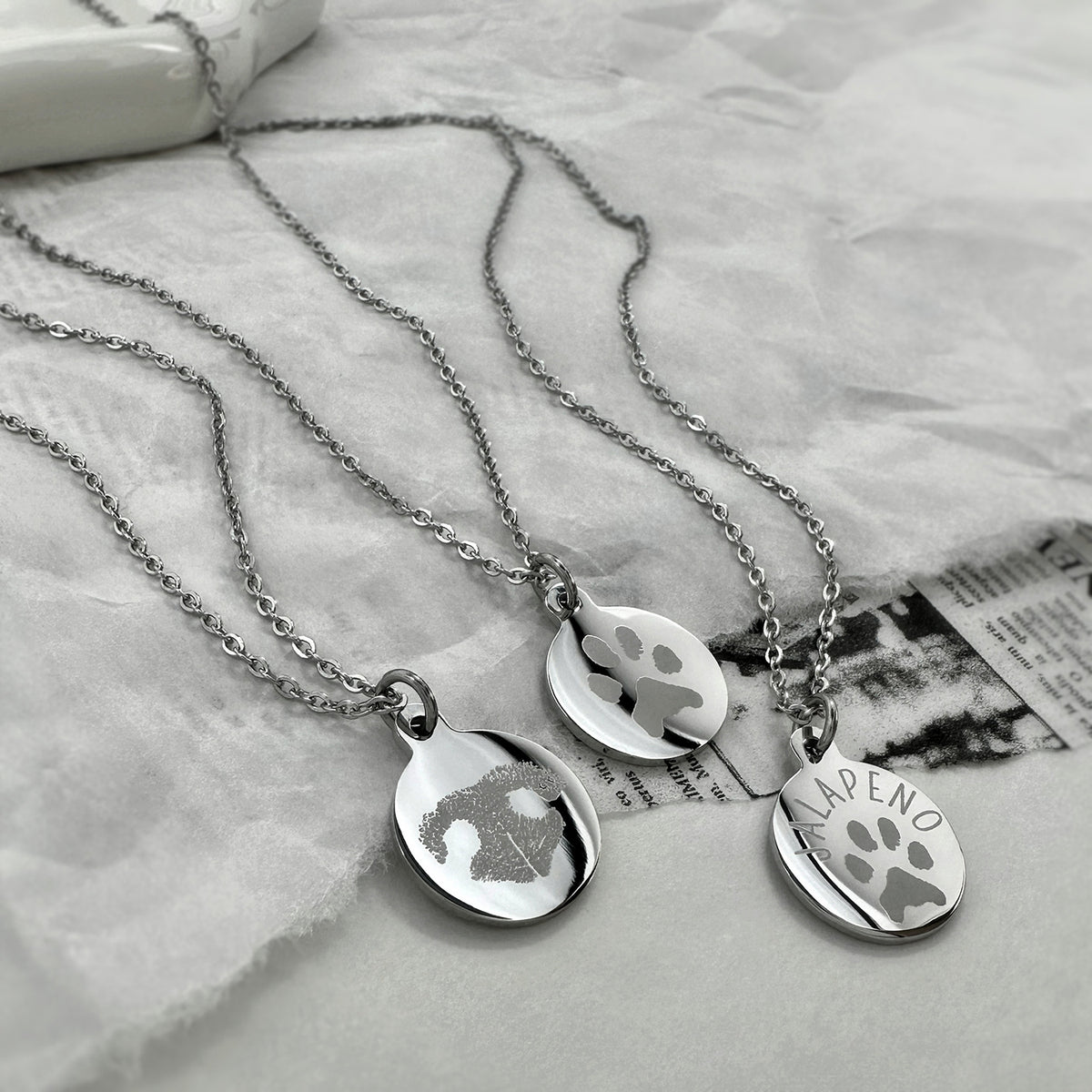 Three silver chain necklaces with round custom engraved actual personalized pet paw print, nose print, and custom name. 