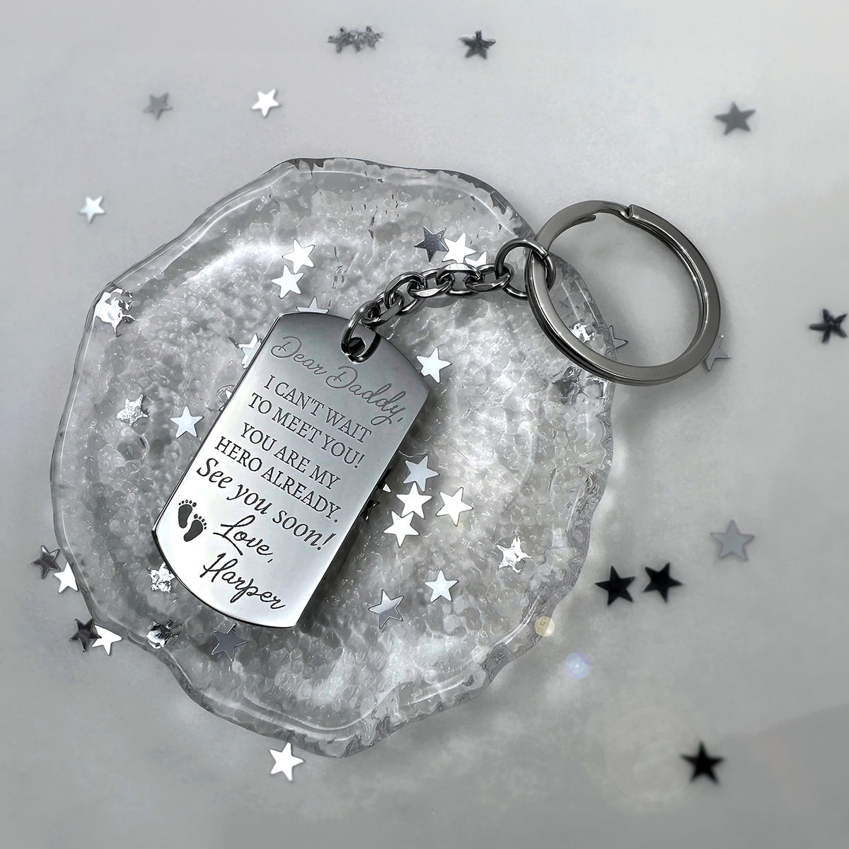 Pregnancy announcement dog tag keychain engraved with “Dear Daddy, I can’t wait to meet you, you are my hero already” displayed with star accents